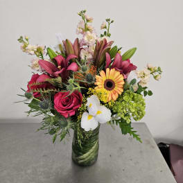 Mixed bouquet in a glass vase with pink, white, yellow, and green flowers