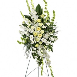 Tall white and pale yellow funeral spray on a stand
