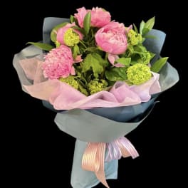 Pink peony bouquet wrapped in pastel paper with ribbon