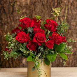 Arrangement of red roses in a gold cylinder vase on a marble surface
