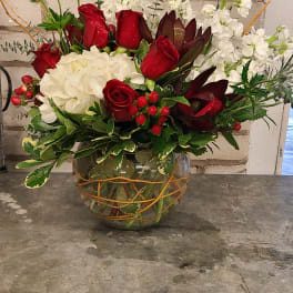 Red roses and white flowers arranged in a glass vase