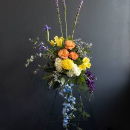 Tall mixed flower arrangement with orange, yellow, blue, and purple blooms