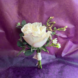 Cream rose boutonniere with small white buds and ribbon on a purple background