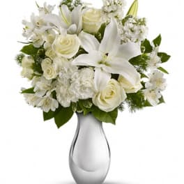 White lilies and roses arranged in a clear glass vase