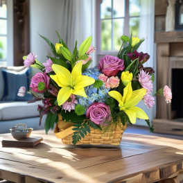 Basket arrangement with yellow lilies, pink roses, and blue hydrangeas