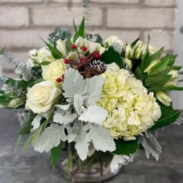 White floral arrangement in a glass vase with roses and hydrangeas