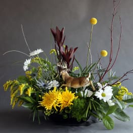 Mixed floral arrangement with a deer figurine in a low black container