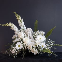 White floral arrangement with a cherub figurine in a black container