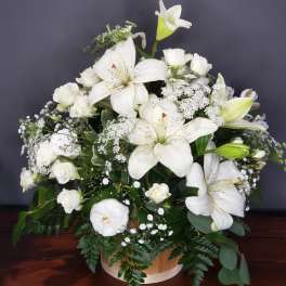 White lilies and roses arranged in a round basket