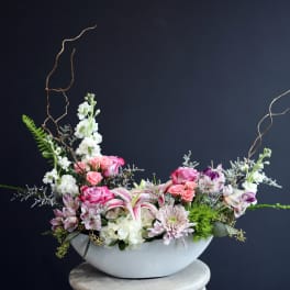 Pink and white floral arrangement in a white bowl vase