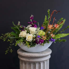 White roses and purple flowers in a white bowl vase