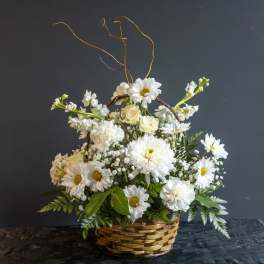 White flowers arranged in a wicker basket with tall curly branches