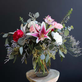 Mixed bouquet with pink lilies, carnations, and eucalyptus in a glass vase