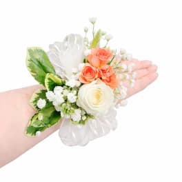 Peach spray rose and white rose wrist corsage with baby's breath and ribbon on a person's arm