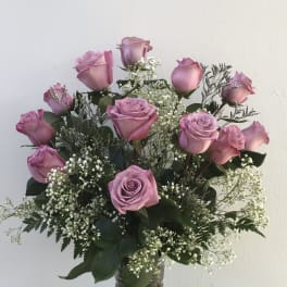 Pink roses arranged in a clear glass vase with white filler flowers