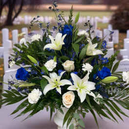White lilies, blue roses, and white carnations in a white vase