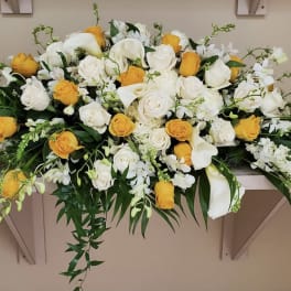 Long floral arrangement of white and yellow roses with white lilies