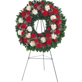 Round standing wreath of red and white carnations on a metal easel