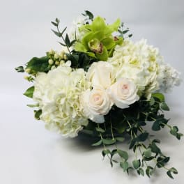 White hydrangeas and pale roses with a green orchid in a low bouquet