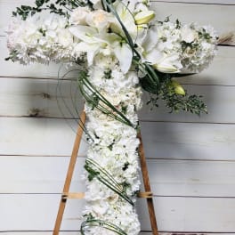White floral cross arrangement on a wooden easel