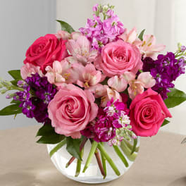 Pink and purple mixed bouquet of roses and alstroemeria in a clear glass vase