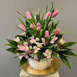 Pink tulips and pale pink alstroemeria in a white basket