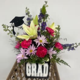 Graduation flower arrangement with a black cap decoration and "GRAD" sign
