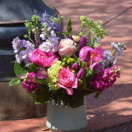 Colorful pink and purple flower arrangement in a white ceramic vase outdoors