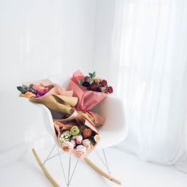 Two wrapped bouquets on a white chair by a bright window.