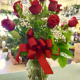 Red roses in a glass vase with a large red ribbon