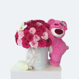 Pink rose bouquet in a silver box beside a pink teddy bear
