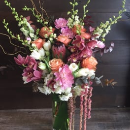 Tall mixed bouquet with pink, peach, and white flowers in a glass vase