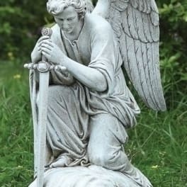 Stone angel statue kneeling in grass with folded wings