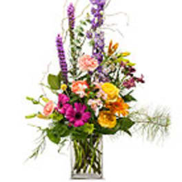 Tall mixed bouquet in a clear glass vase with purple, pink, and yellow flowers