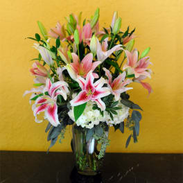 Pink and white lilies arranged in a clear glass vase
