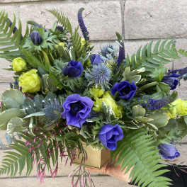 Blue and yellow floral arrangement in a gold box