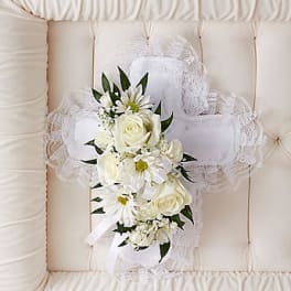 White floral cross with roses and daisies on a tufted cushion