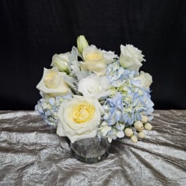 White roses and pale blue hydrangeas in a glass vase