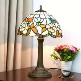 Stained-glass table lamp beside a small potted flower arrangement