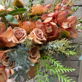 Peach roses and orange orchids in a terracotta vase