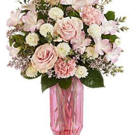 Pink roses and white flowers arranged in a pink glass vase