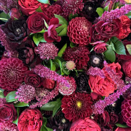 Dense bouquet of burgundy and pink flowers with green leaves