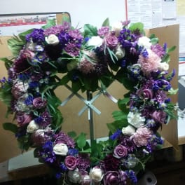 Purple and white floral wreath on a metal stand