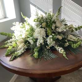 Large white floral arrangement with roses and snapdragons on a table