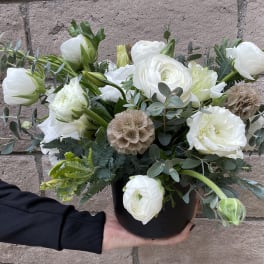 White ranunculus bouquet in a black container with eucalyptus
