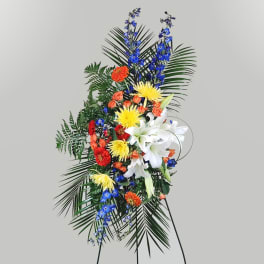 Tall standing floral spray with white lilies, blue flowers, and orange blooms
