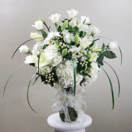 White floral bouquet in a glass vase with a sheer ribbon bow