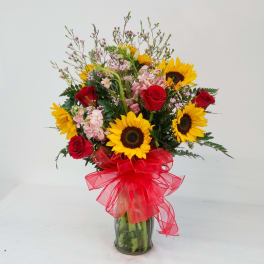 Bouquet of sunflowers and red roses in a glass vase with a red ribbon