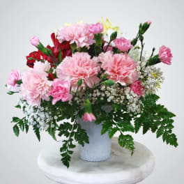 Pink carnations and red flowers in a white vase
