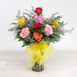 Mixed roses in a glass vase with a yellow ribbon bow